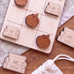 a wooden tic-tac-toe board with wooden apple and book shapes, along with a white cloth and a white bag.