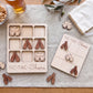 a wooden game board and wooden game pieces, specifically beer mug icons, arranged on a table. There is also a glass of beer visible in the background.