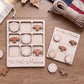 a wooden tic-tac game set with wooden pieces shaped like birds, specifically "Marines", arranged on a wooden surface. There is also a rope and some leaves in the background.