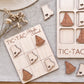 a wooden tic-tac game with wooden sailboat pieces, placed on a beige surface.
