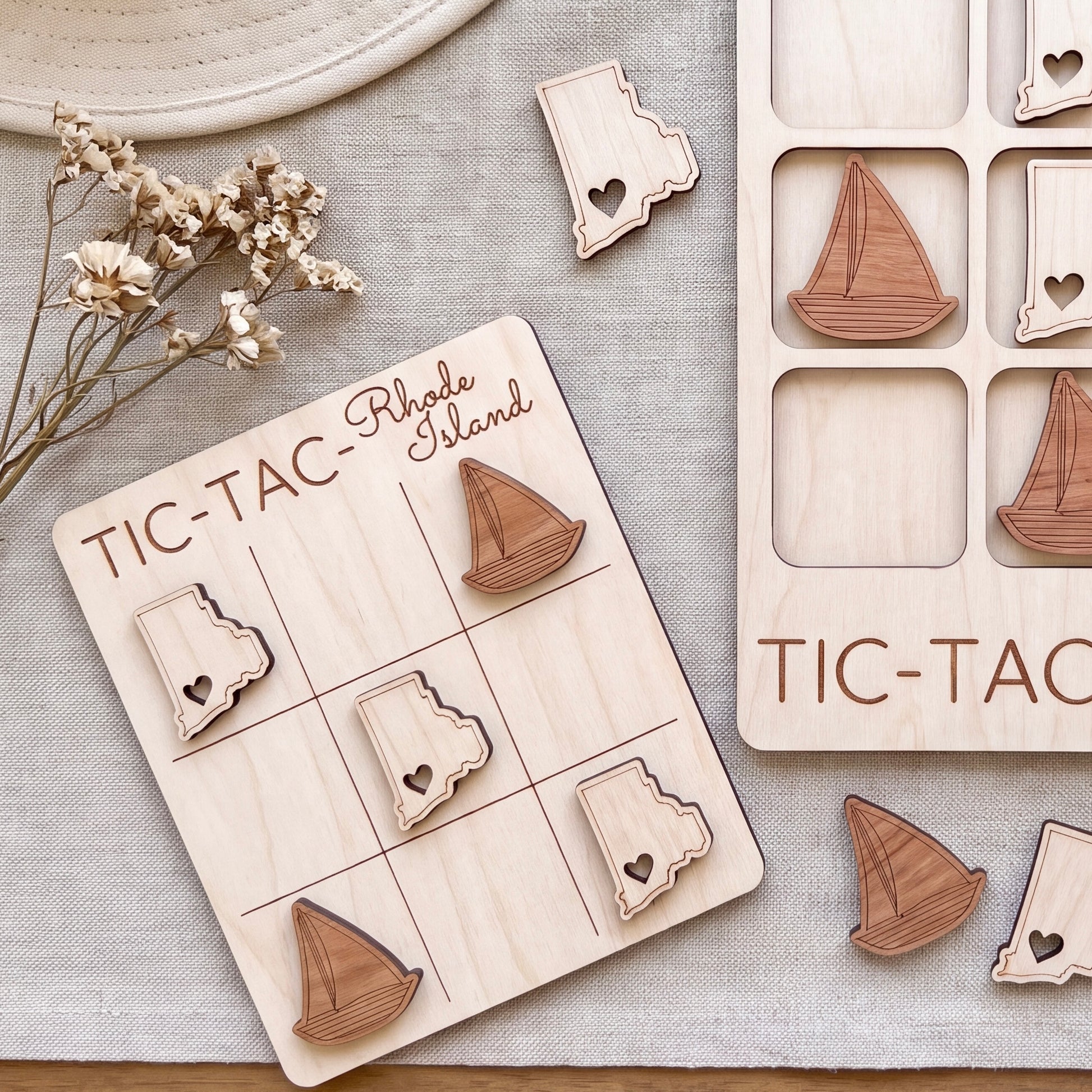 a wooden tic-tac game with wooden sailboat pieces, placed on a beige surface.