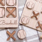 a wooden game board with baseball-themed pieces, including a tic-tac-toe board and a baseball bat and ball.
