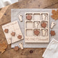 a wooden tic-tac game with Vermont-themed pieces, including a game board and pieces, as well as some autumn leaves scattered around the table.