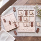 a wooden game board and wooden pieces shaped like rabbits, with the word "TIC-TAC-Louisiana" written on them. The game board and pieces are placed on a wooden surface, surrounded by some flowers.