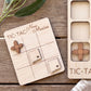 a wooden game board with a tic-tac game and two wooden pieces shaped like states of the United States.