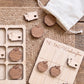 a wooden tic-tac game with wooden pieces shaped like apples, placed on a woven mat.