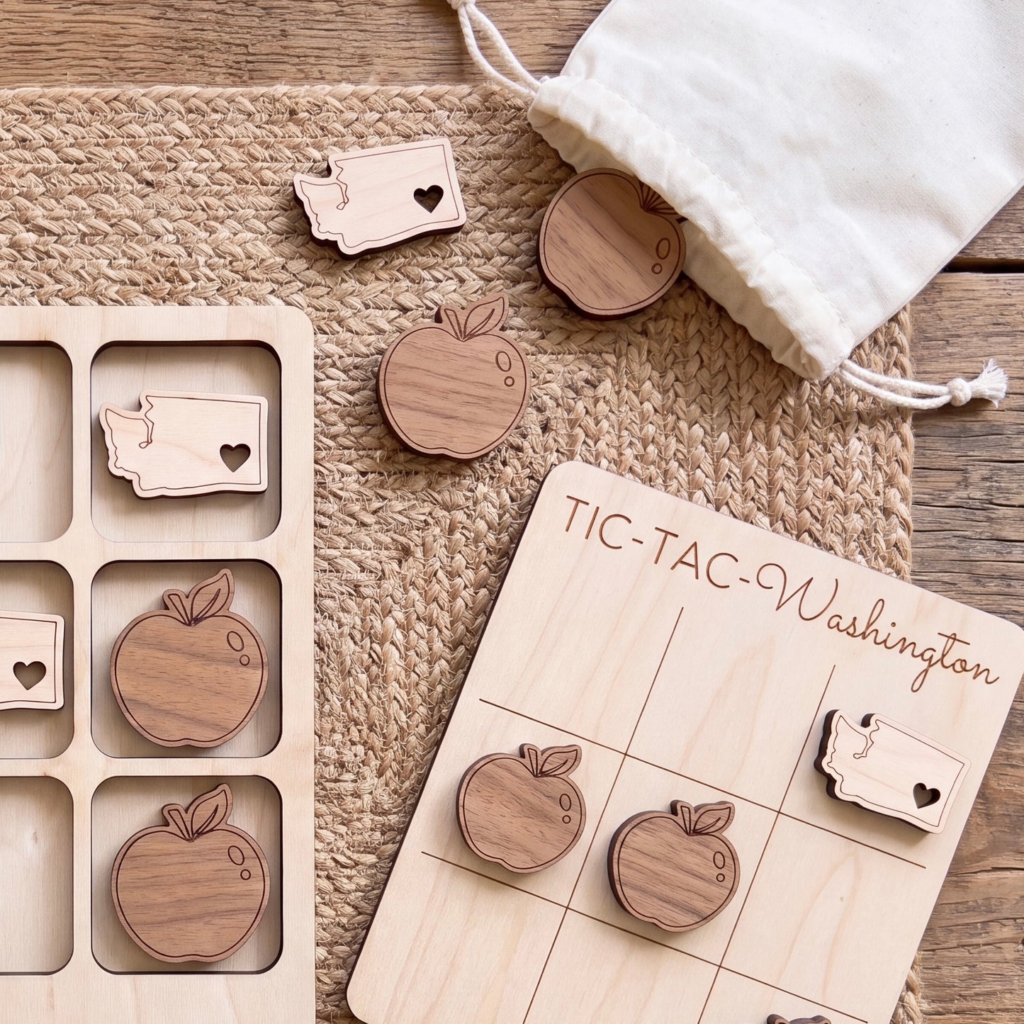 a wooden tic-tac game with wooden pieces shaped like apples, placed on a woven mat.