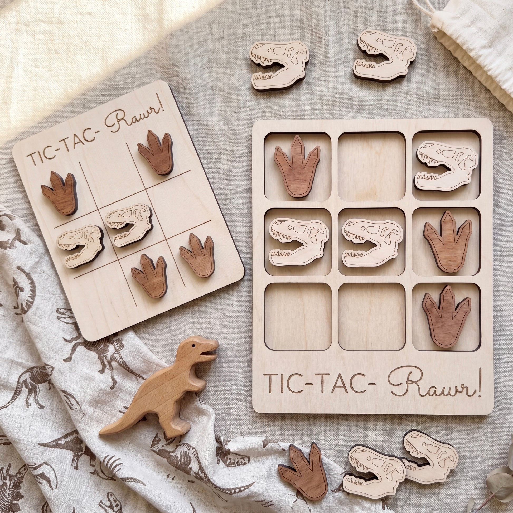 a wooden tic-tac game with dinosaur footprints and dinosaur toys, along with a wooden dinosaur toy.