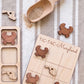 a wooden tic-tac game board with a Maryland state on it, along with several wooden crab-shaped tiles and a wooden scoop.