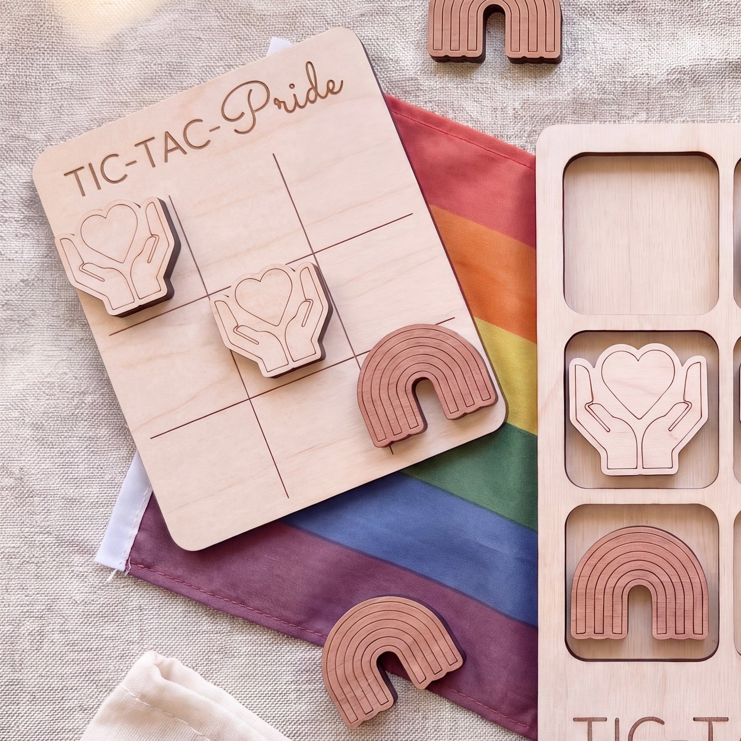 a wooden tic-tac game with a rainbow flag and wooden hearts as game pieces.