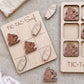 a wooden tic-tac game with a surf theme, including a wooden board with a surfboard and several wooden pieces shaped like surfers.