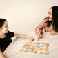 Two young girls are sitting at a marble table, engaged in a game with wooden blocks.
