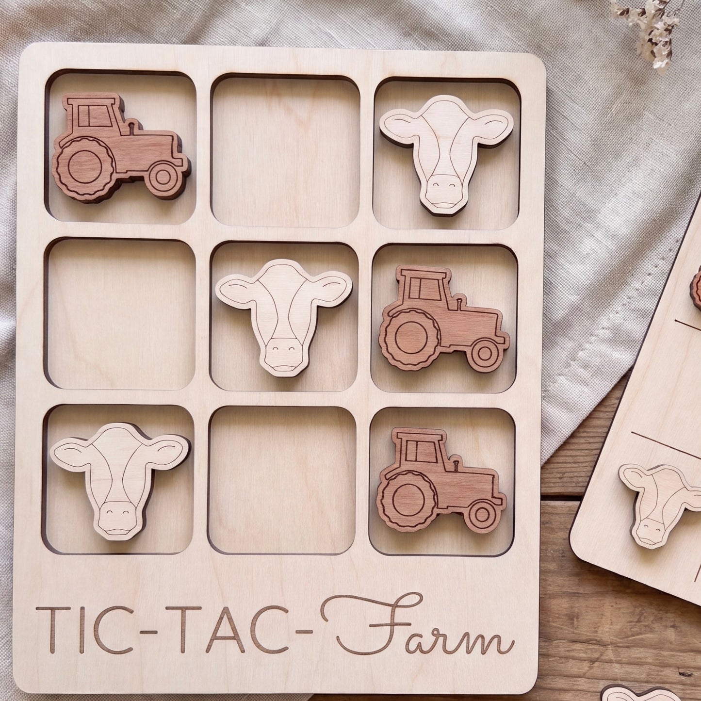 A wooden tic-tac game board with farm animal tiles, including a tractor and a cow, arranged in a grid pattern.