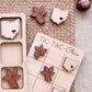 a wooden tic-tac game board with various wooden pieces shaped like flowers and states, including Ohio, placed on it.