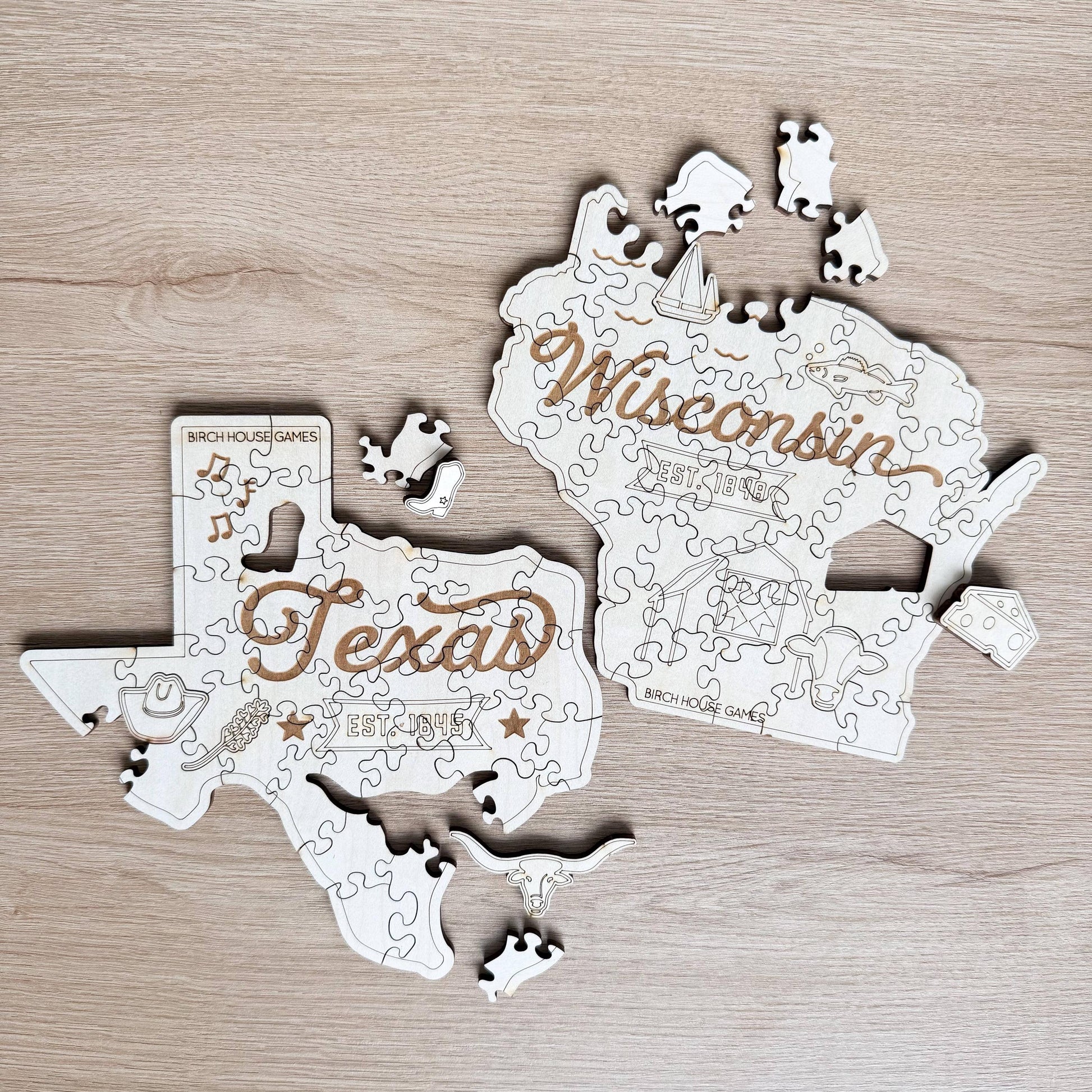 two wooden puzzle pieces shaped like the states of Texas and Wisconsin, with the words "Texas" and "Wisconsin" written on them.