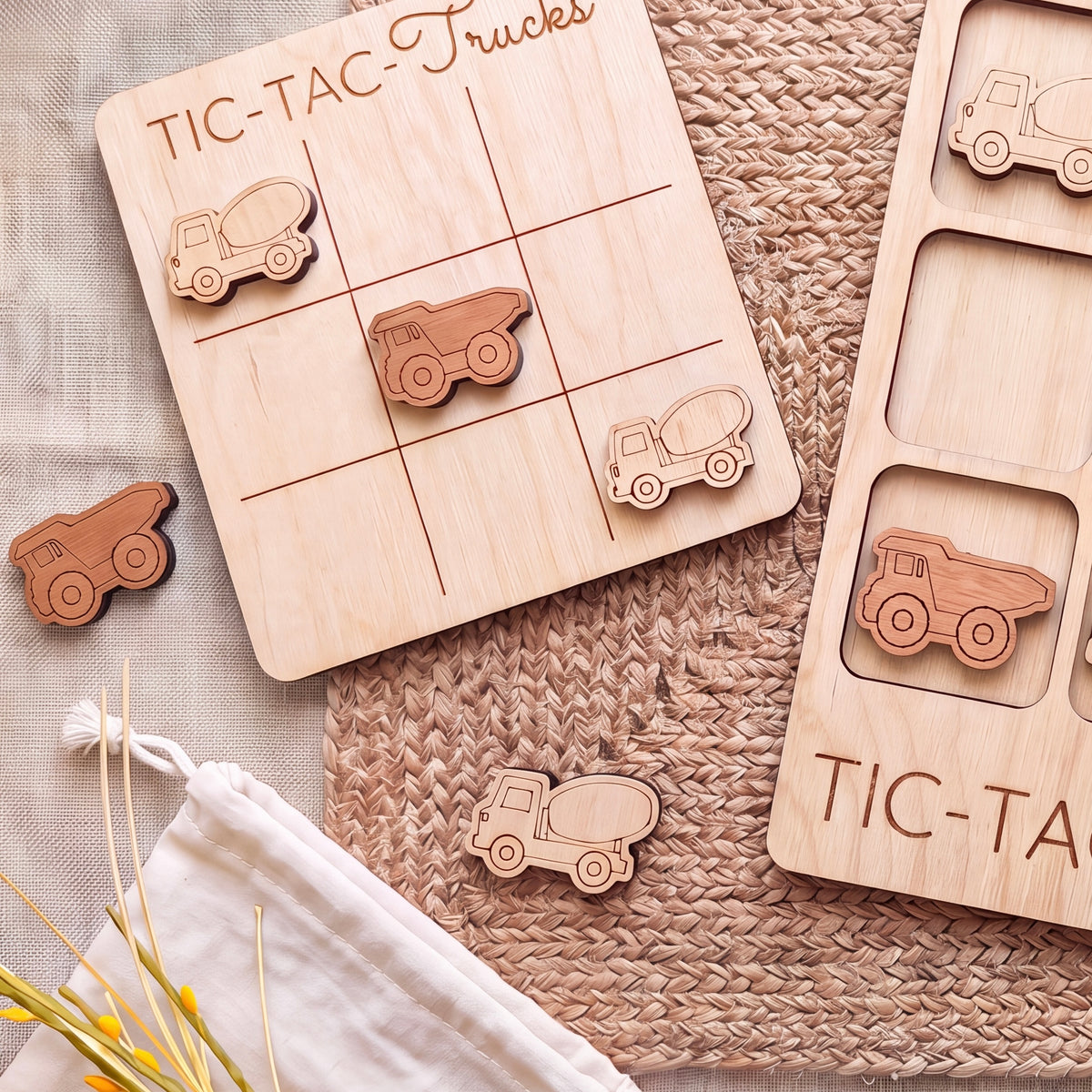 a wooden tic-tac game board with wooden trucks and a white cloth on a woven surface.