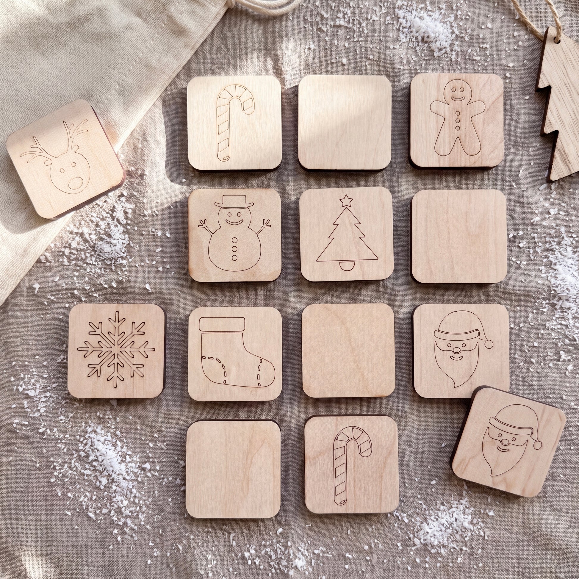 A collection of wooden coasters featuring various Christmas-themed designs, including a reindeer, candy cane, snowman, Christmas tree, Santa Claus, and a snowflake.