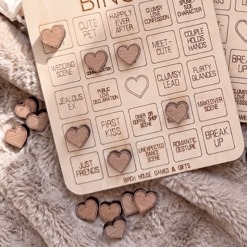 a wooden bingo board with various heart-shaped stickers attached to it, along with some additional heart-shaped stickers scattered around the board.