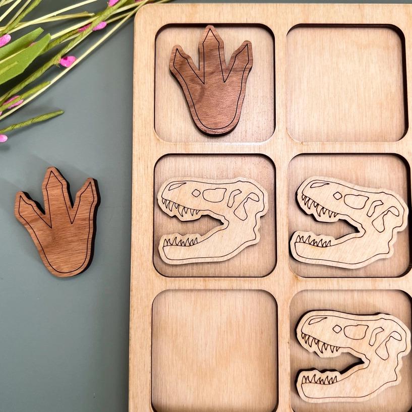 a wooden tray with four wooden dinosaurs in it