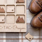 a wooden tic-tac game board with the word "Oregon" written on it, along with a pair of brown hiking boots placed next to it.