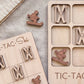 a wooden tic-tac game with a snowboard and skis as game pieces, and a wooden sign with the word "TIC-TAC" written on it.