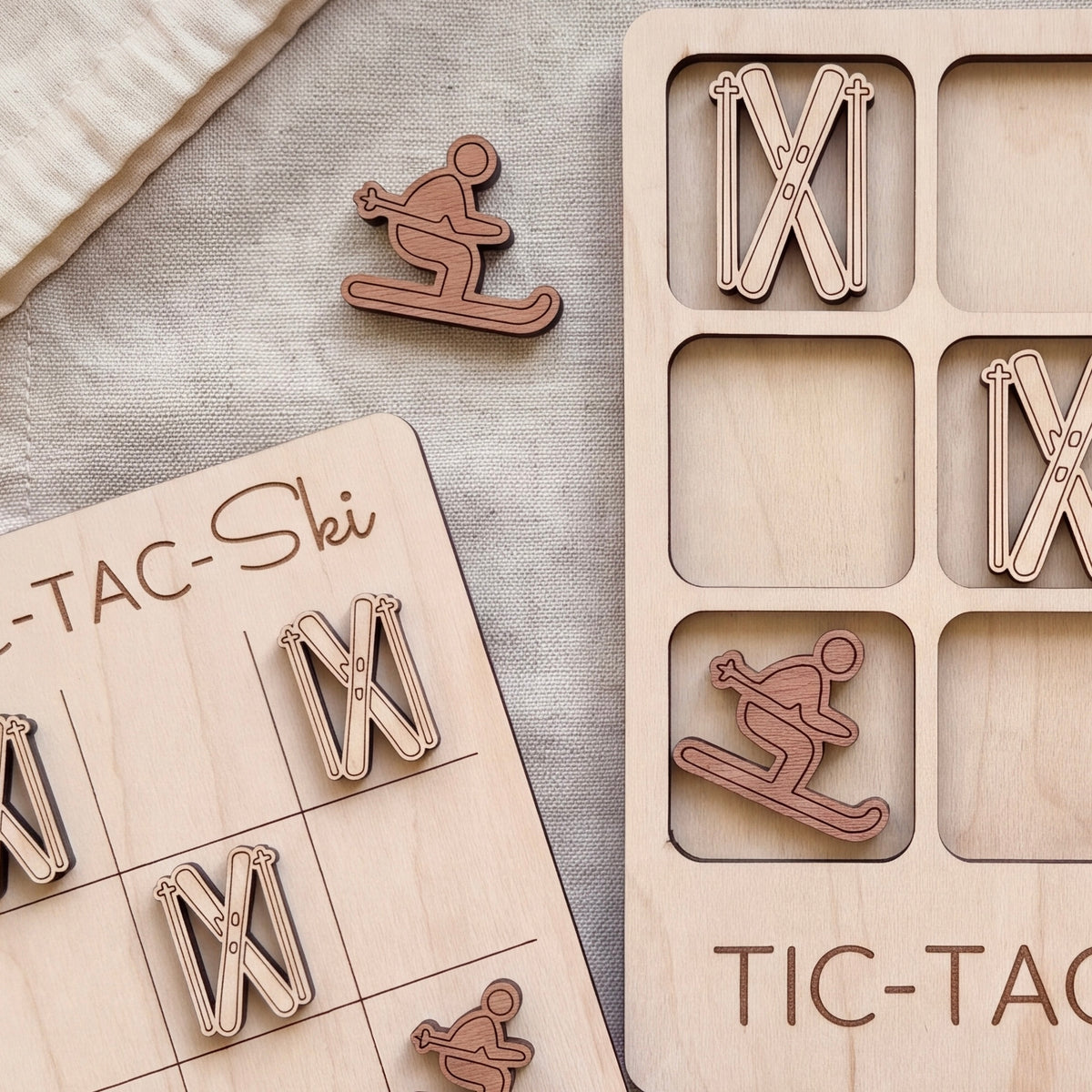 a wooden tic-tac game with a snowboard and skis as game pieces, and a wooden sign with the word "TIC-TAC" written on it.