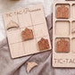 a wooden tic-tac game board with wooden pieces shaped like castles, and a wooden tic-tac game board with wooden pieces shaped like crowns.