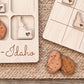 a wooden game board with a potato cutout and the word "Idaho" written on it. There are also two wooden potato cutouts on the ground.