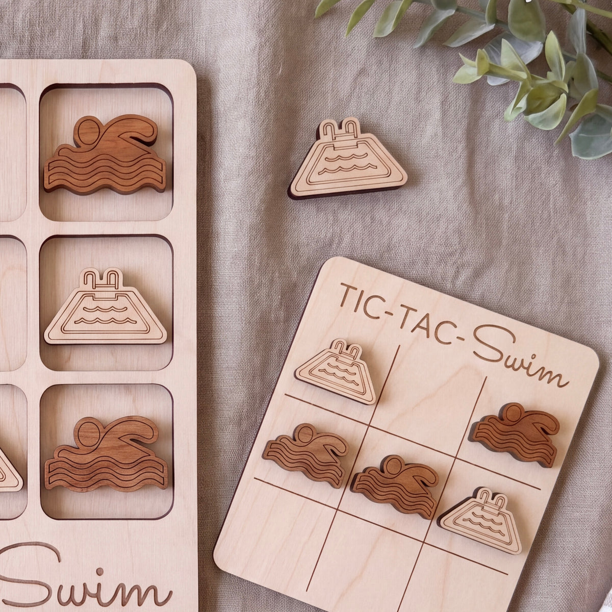 a wooden tic-tac game with swimming-themed tiles and a wooden board with a "TIC-TAC-Swim" title.