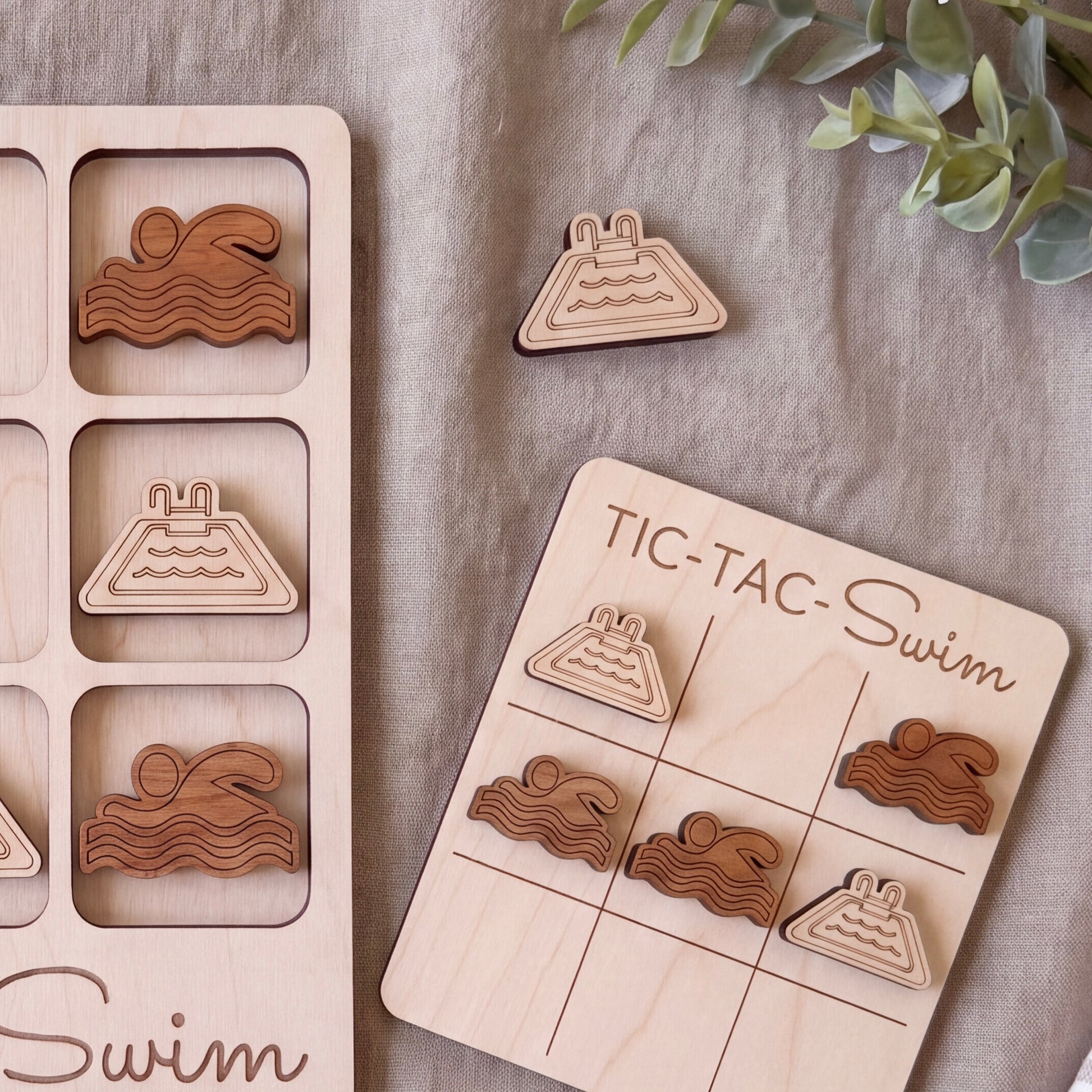 a wooden tic-tac game with swimming-themed tiles and a wooden board with a "TIC-TAC-Swim" title.