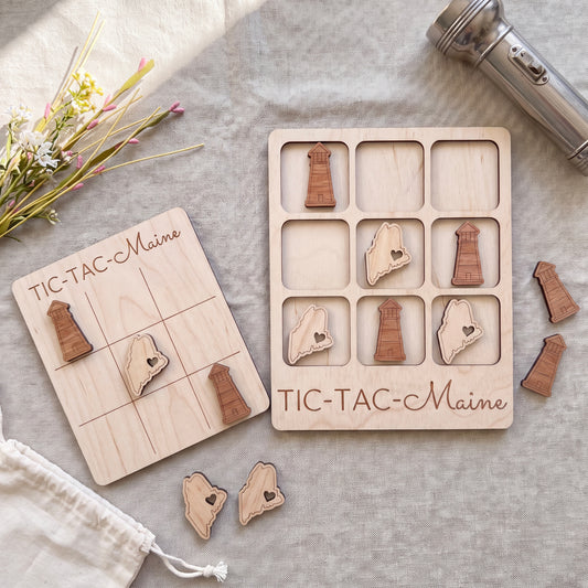 a wooden tic-tac game board with wooden pieces shaped like states in Maine, and a metal flashlight on a table.
