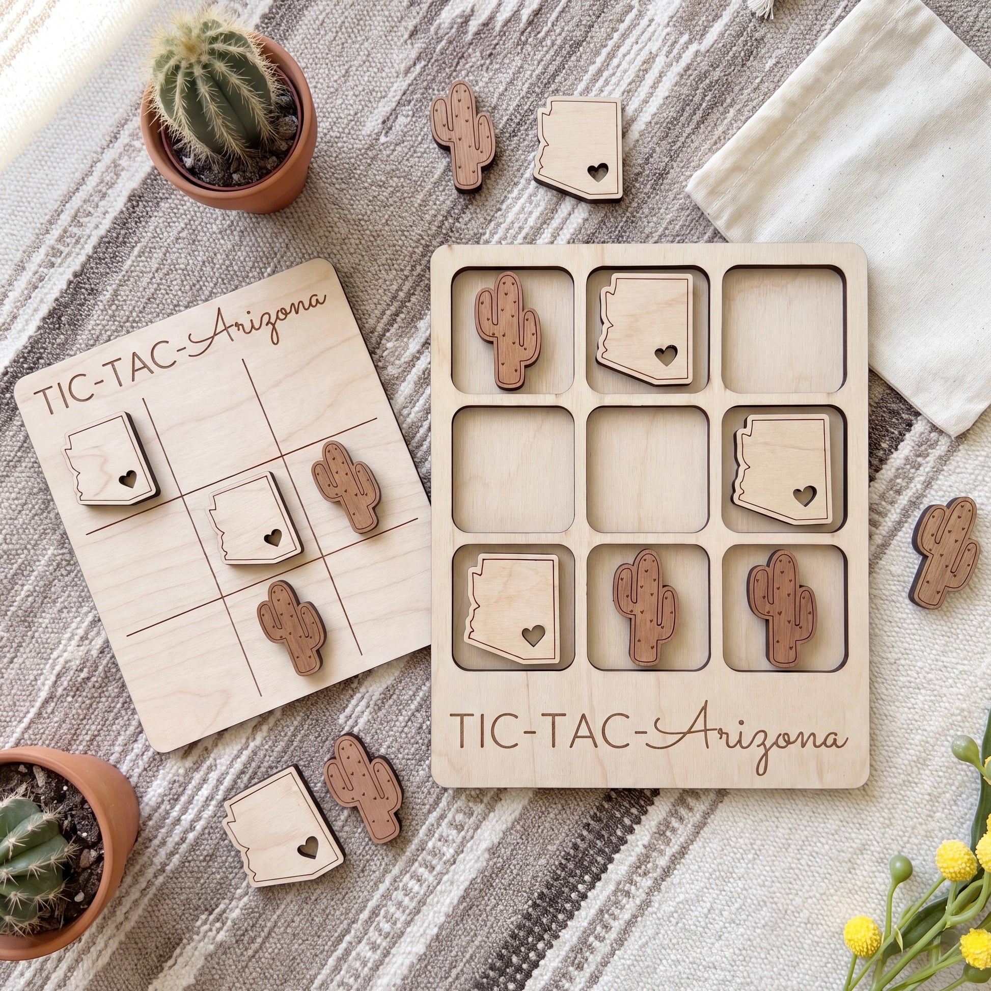 a wooden tic-tac game with Arizona state icons, including a cactus, placed on a table alongside other decorative items such as potted plants and a white cloth.
