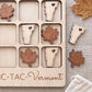A wooden tic-tac game with wooden pieces shaped like states and leaves, including Vermont, placed on a wooden surface.