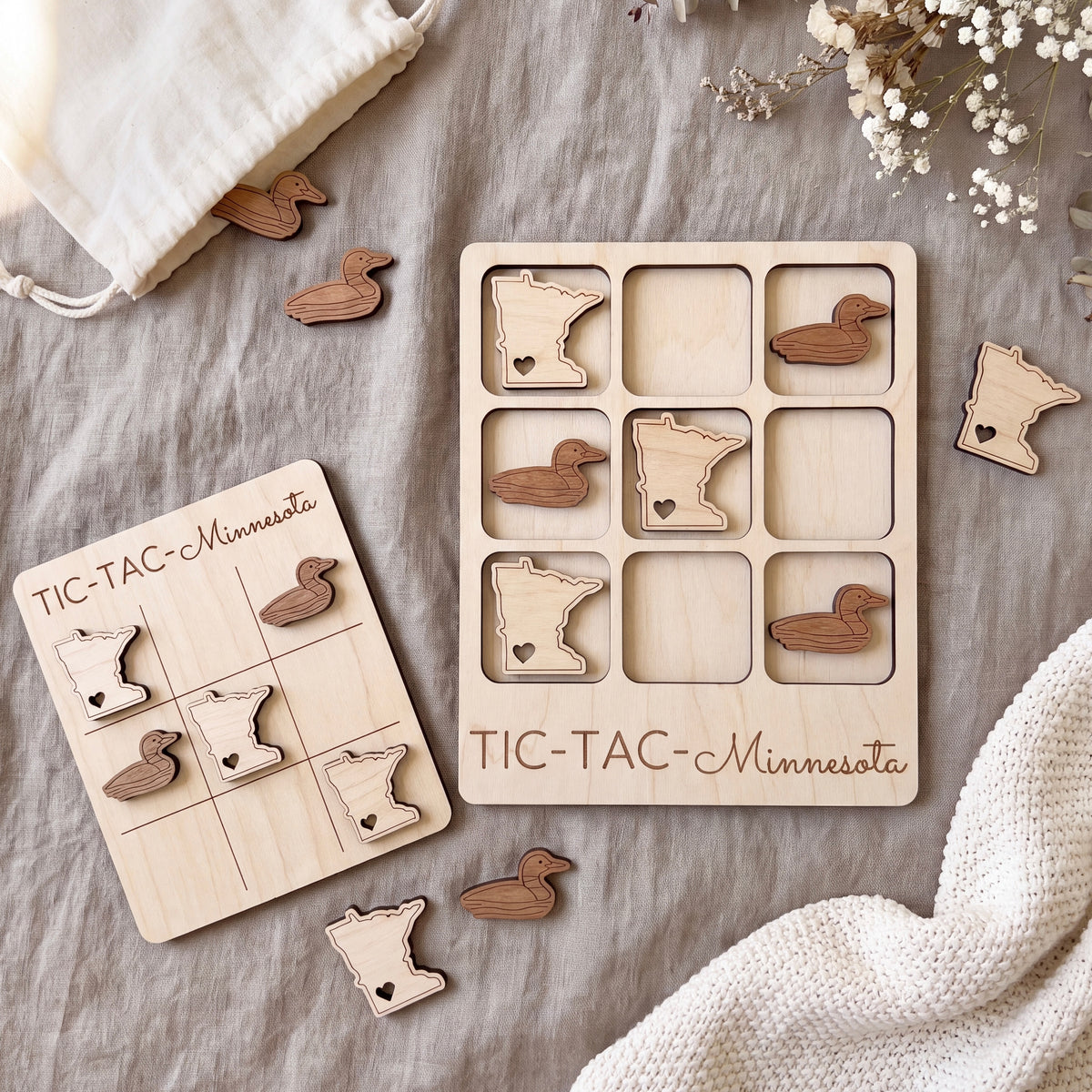 a wooden tic-tac game set with Minnesota duck-shaped tiles, placed on a grey cloth.