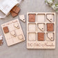 a wooden Tic-Tac- Nevada game board and game pieces, along with a white cloth and some flowers.