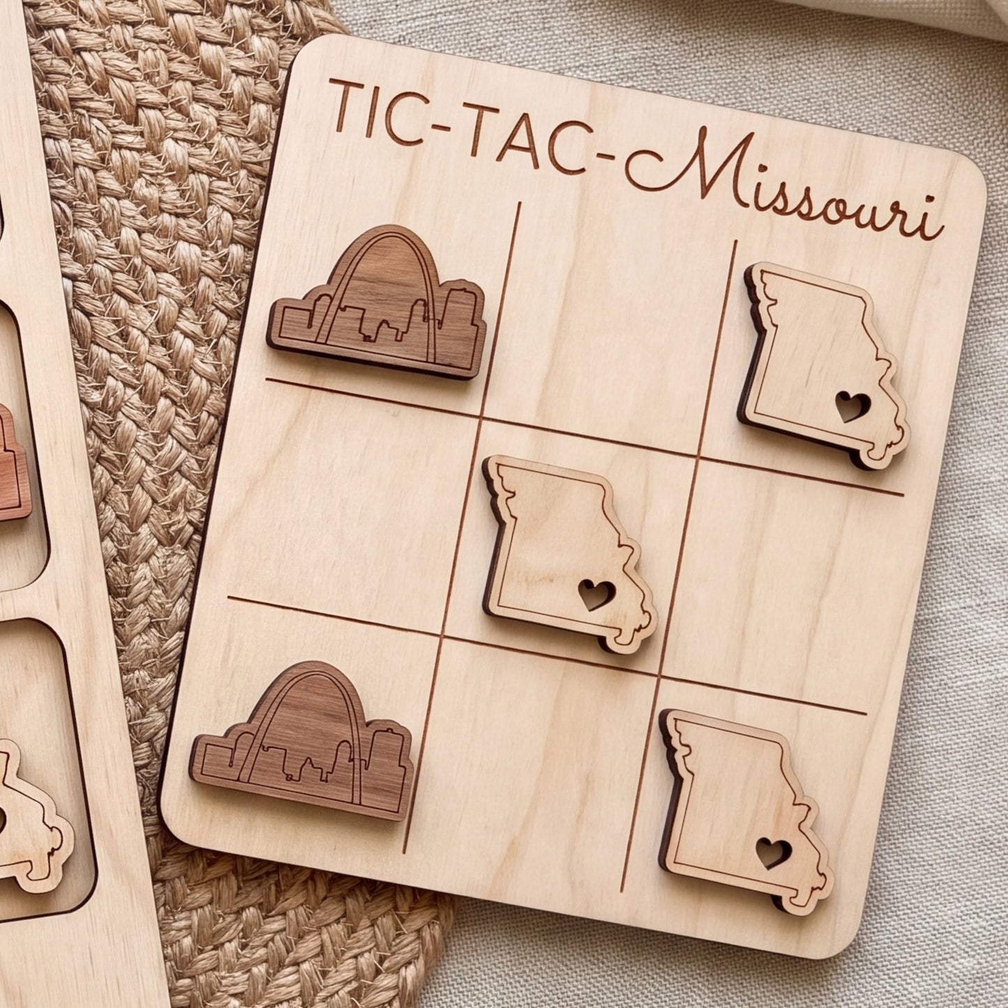 A wooden tic-tac game board with the state of Missouri marked on it, featuring wooden tic-tac pieces shaped like the state.