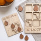 a wooden tic-tac game with wooden pieces shaped like Florida and an empty wooden board with the same design. There are also some oranges visible in the background.