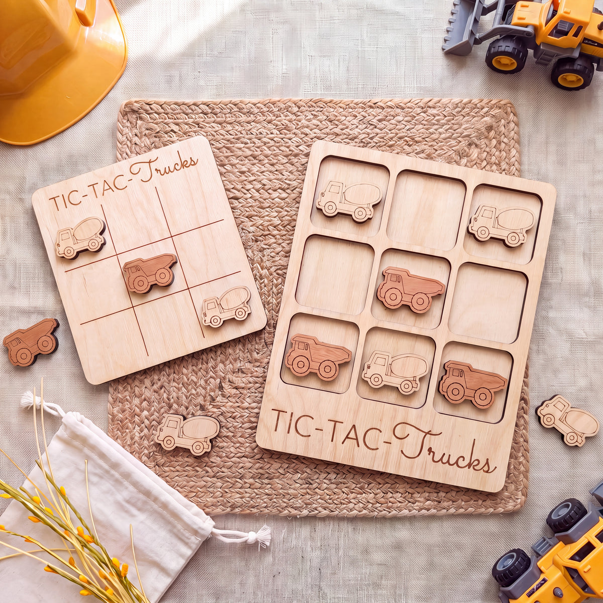 a wooden tic-tac truck game with various trucks and a yellow construction helmet on a woven placemat.
