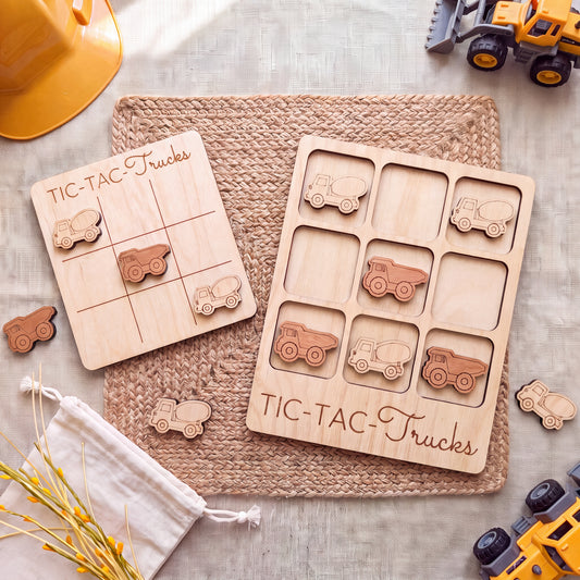 a wooden tic-tac truck game with various trucks and a yellow construction helmet on a woven placemat.