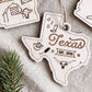 a wooden ornament shaped like the state of Texas, with various symbols and text related to the state's culture and history.