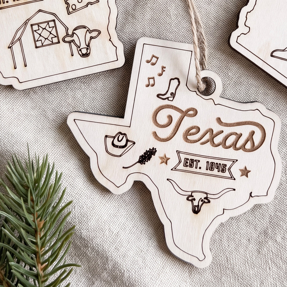 a wooden ornament shaped like the state of Texas, with various symbols and text related to the state's culture and history.