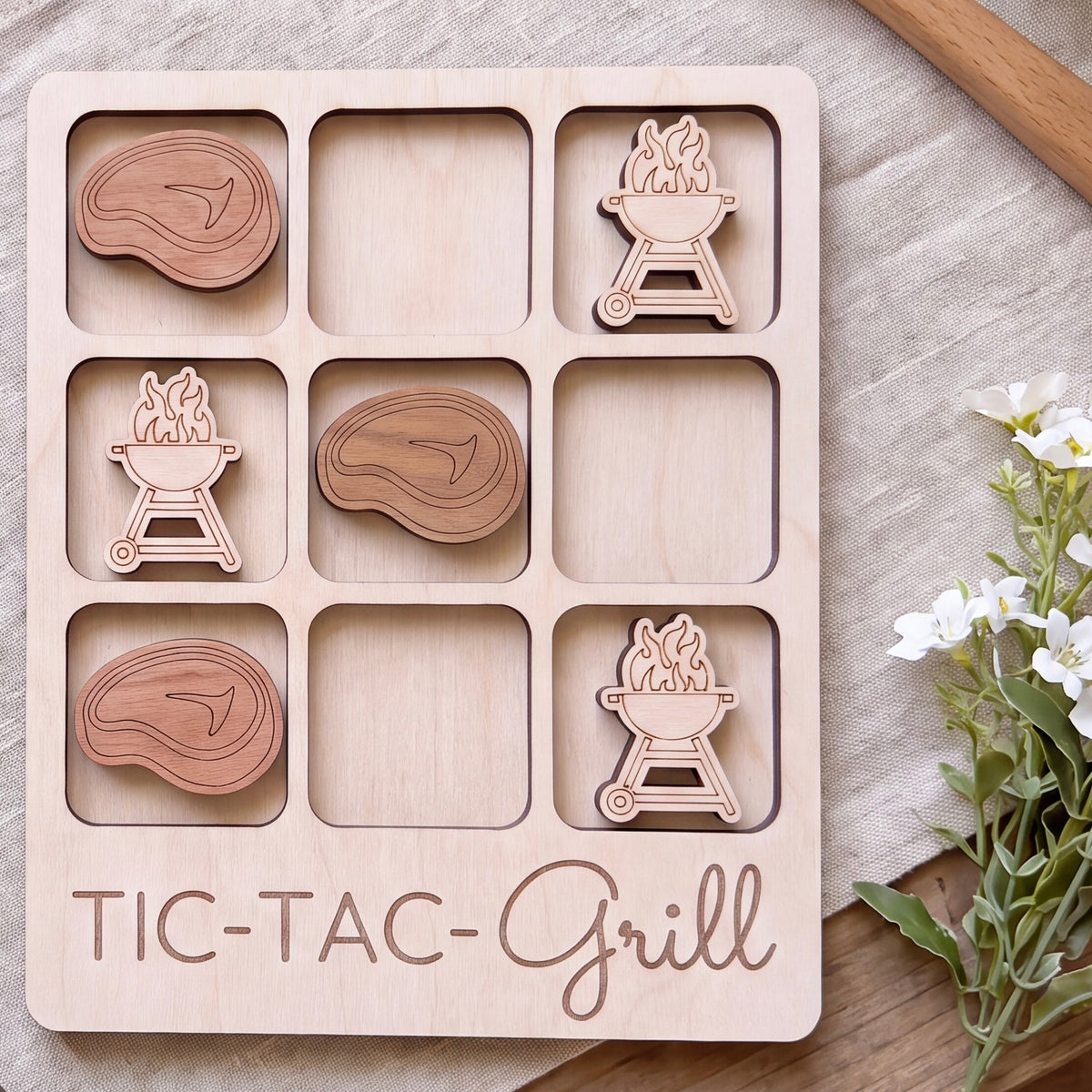A wooden tic-tac-grill game board with wooden pieces shaped like different types of meat and a wooden tic-tac box.