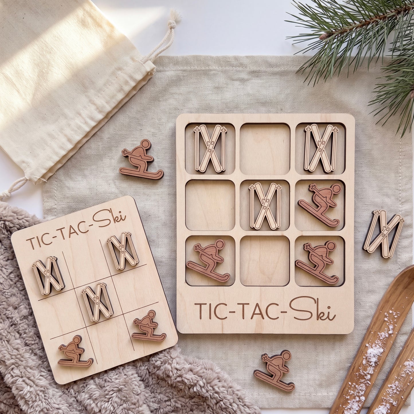 a wooden tic-tac game with a ski theme, including a game board and pieces, as well as some additional skiing-related items such as a pair of skis and a pine tree.