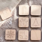 A collection of wooden coaster-shaped objects, each featuring a different winter-themed design, including a reindeer, candy cane, snowman, snowflake, and stocking.