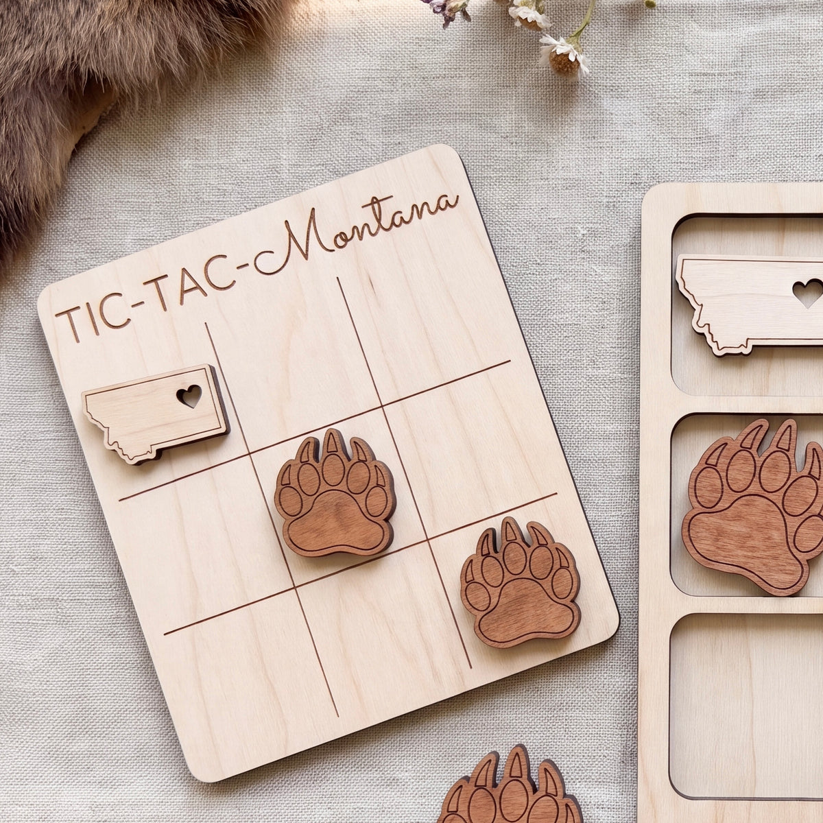 a wooden tic-tac game board with a Minnesota state shape cutout, along with several wooden paw print shapes.