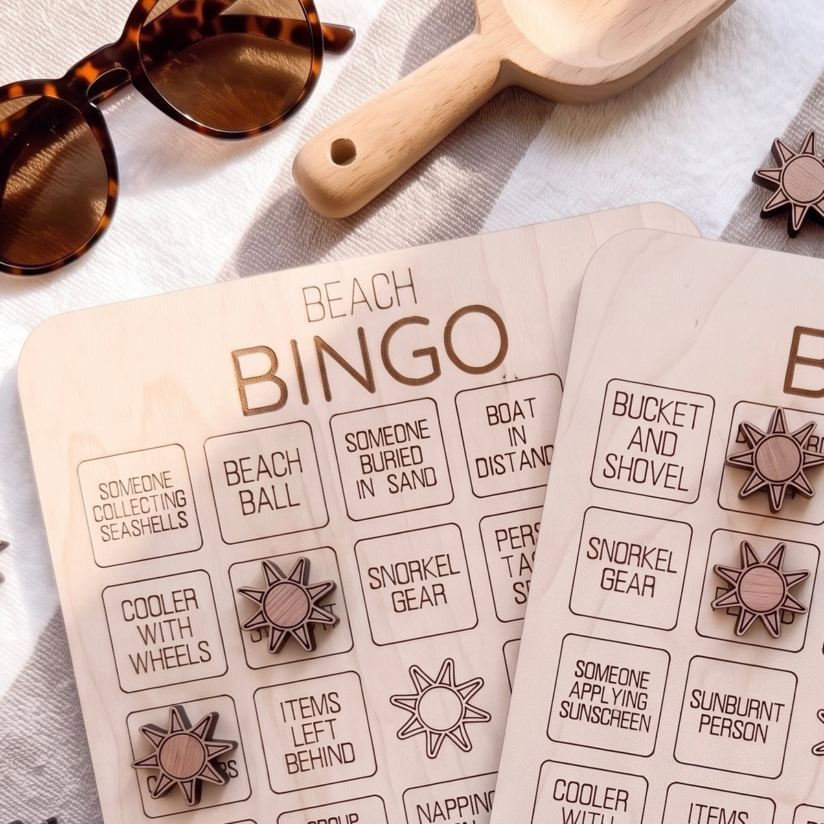 a wooden bingo board with various beach-themed items and a pair of sunglasses on a white cloth.