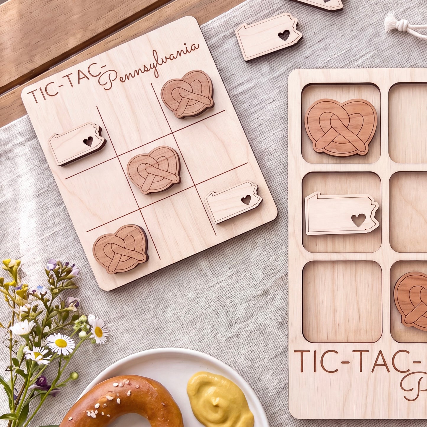 a wooden tic-tac game with Pennsylvania state shapes on it, along with a plate of food and some flowers.