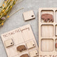 a wooden Tic-Tac-To-Win-Dix board game with wooden pieces shaped like buffalo and a wooden card with a heart cutout.