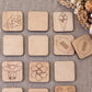 a collection of wooden coasters or tiles with various designs, including a cow, a football, and other abstract shapes.
