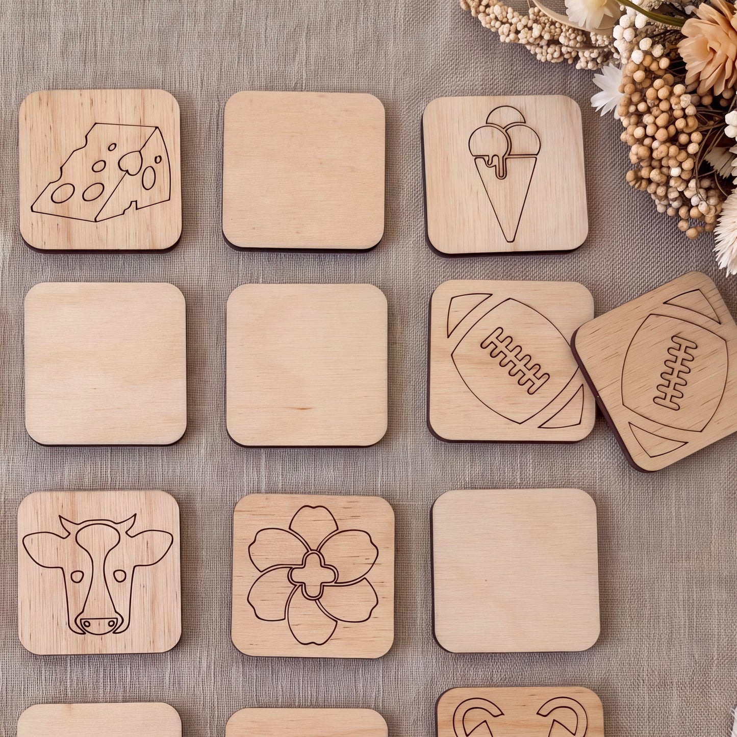 a collection of wooden coasters or tiles with various designs, including a cow, a football, and other abstract shapes.